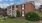 a brick building with a lawn and trees in front of it
